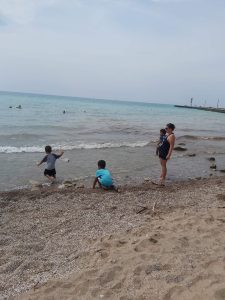 Image is a photo of Chantalle with her three young boys at a beach. 